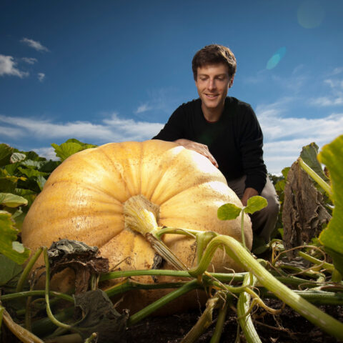 Peter DelNero, a graduate student in biomedical engineering (BME), with a giant pumpkin that he grew at the Dilmun Hill Student Farm (CUAES).