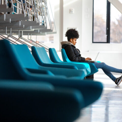 A student soaks up the afternoon sun while working in the Mui Ho Fine Arts Library.