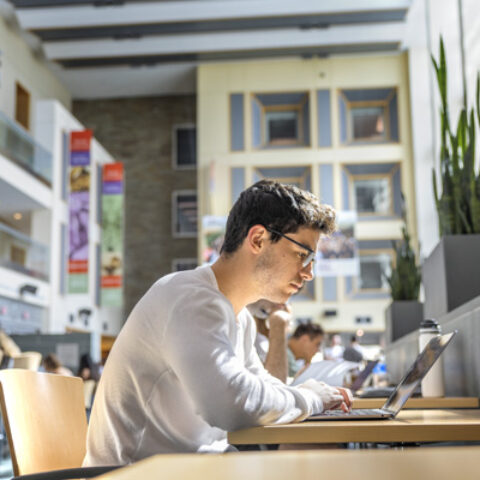 A student works in the atrium of Duffield Hall.