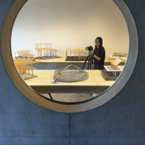 A student in the College of Architecture, Art and Planning moves among structural models while documenting the class works in Milstein Hall.