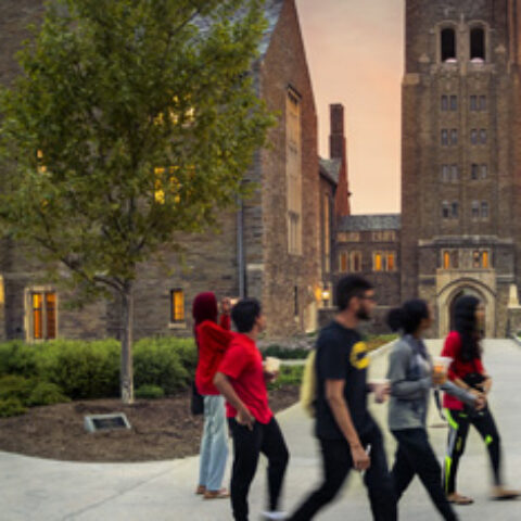 Students walk by Myron Taylor Hall at dusk.